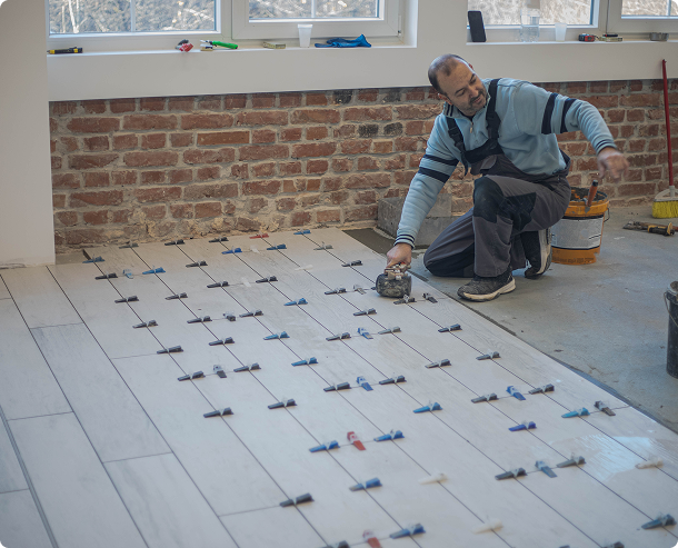 Man installing floor tiles in room